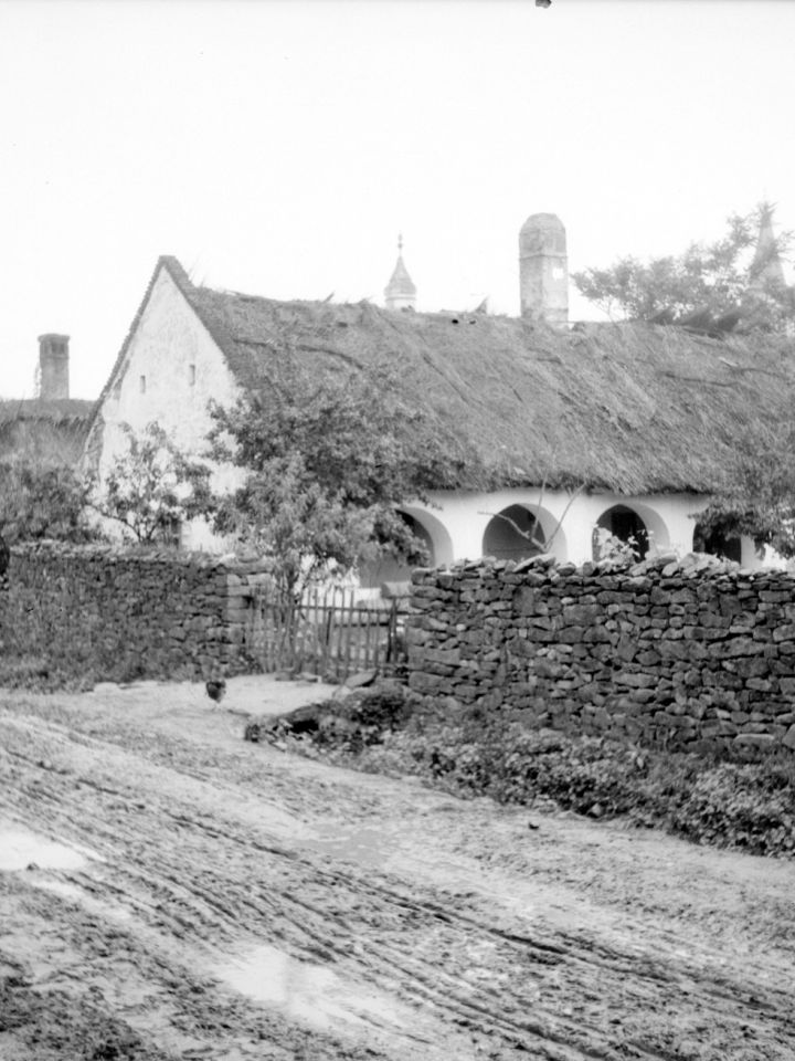 Kővágóörsi kőkerítés, mögötte árkádíves tornácú lakóház. 10591.