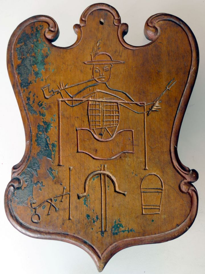 A veszprémi tobakok céhtáblája 1800-ból. A kádban bőröket taposó, pipázó tobak baljában bőrforgató villa, alatta balról: a külü nevű örlőszerkezet, félhold alakú kétnyelű kés, illetve egy vödör, azaz “rocska” látható.  LDM Néprajzi gyűjtemény C.57.